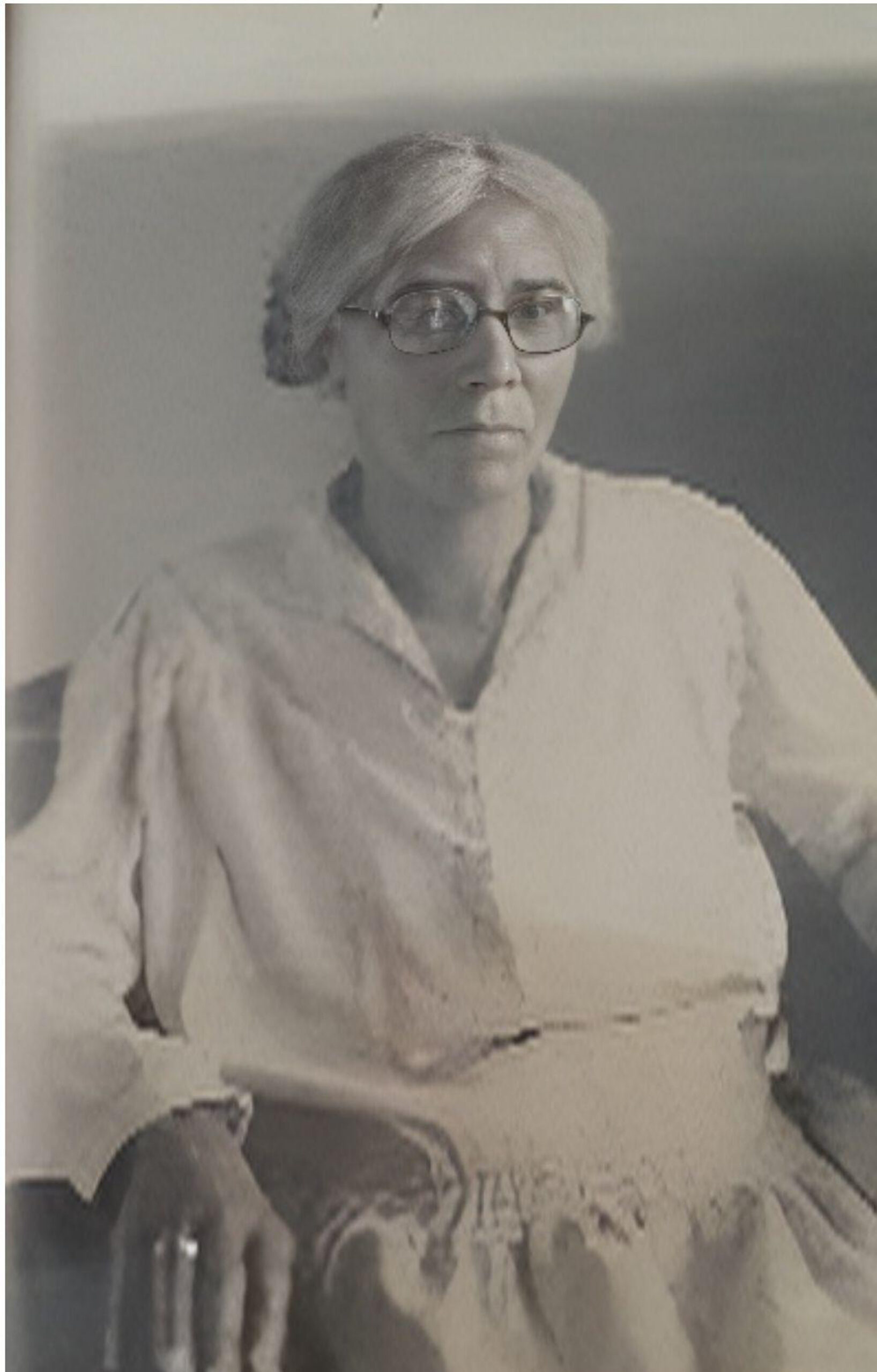 Portrait of Aurelia Godfrey Mitchell (1859 to 1940), a Black Creole woman from Lafayette Parish, Louisiana, who settled in Liberty County, Texas. She is shown seated, wearing a light-colored blouse, with silver hair parted in the center and round wire-frame glasses. Photograph hosted on Find a Grave Memorial ID 90549631.
