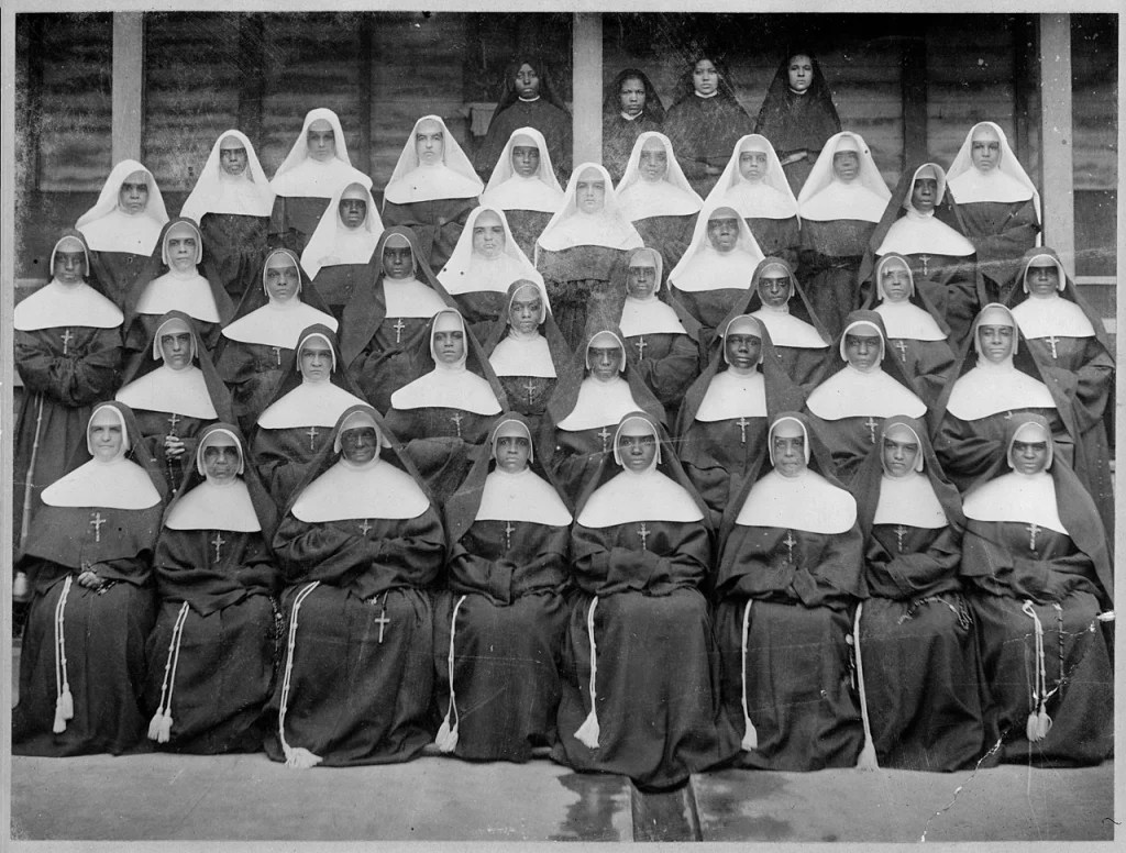 A black-and-white 1900 group photograph of the Sisters of the Holy Family, several rows of Black nuns in dark habits.